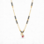 Gold plated mangalsutra necklace with black beads and swirl pendant featuring a ruby red stone and crystal accents.