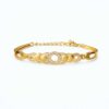 Gold plated bracelet with circular crystal studded design and polished gold discs on white background.